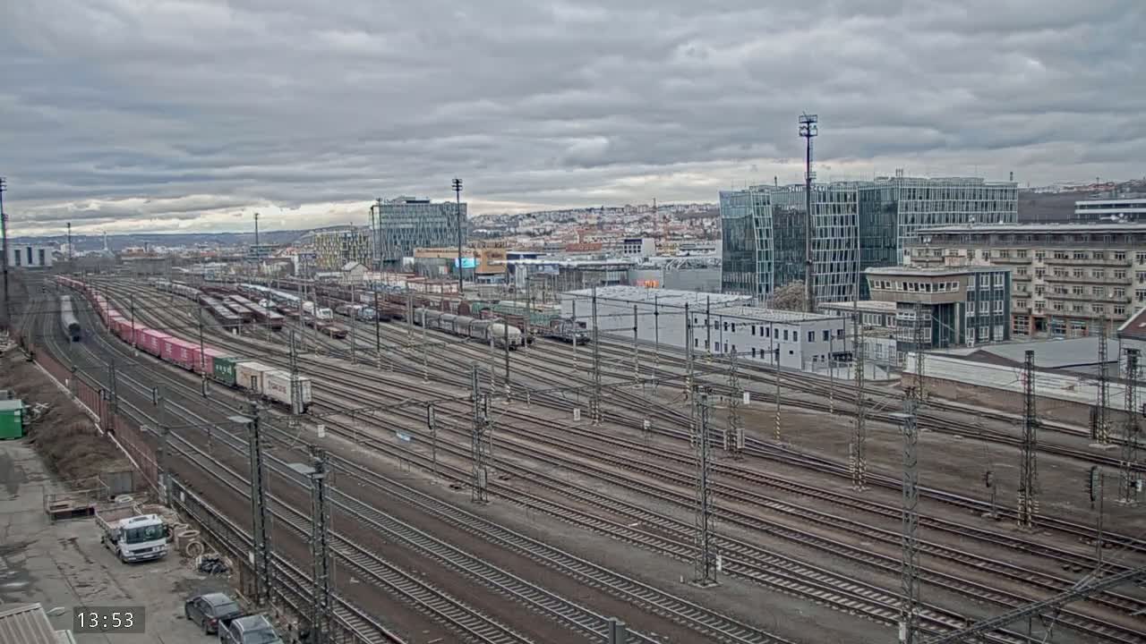 A sprawling railway yard with numerous train cars and tracks under a cloudy sky.