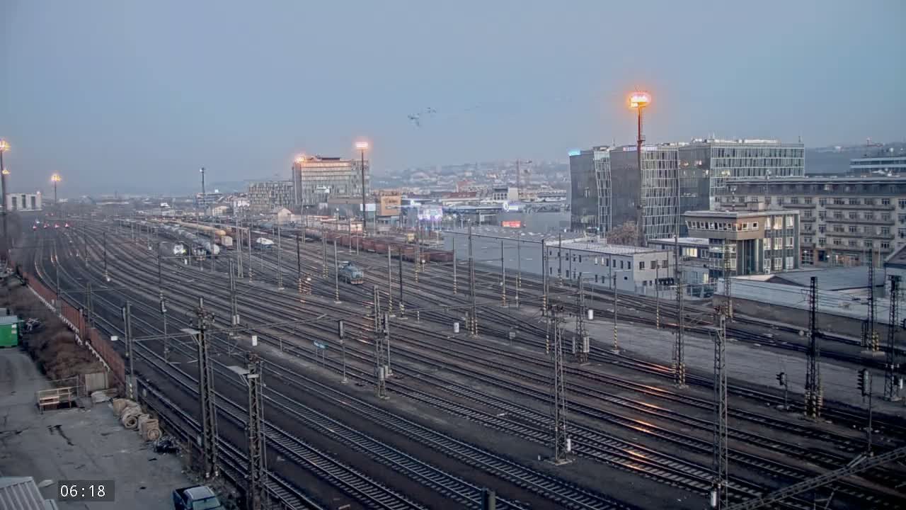 A sprawling railway yard with numerous tracks and trains under an overcast sky.
