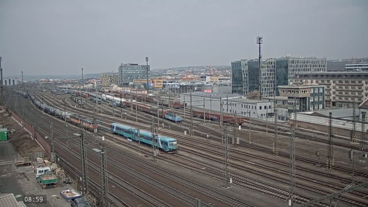 A sprawling railway yard with numerous trains and freight cars under an overcast sky.