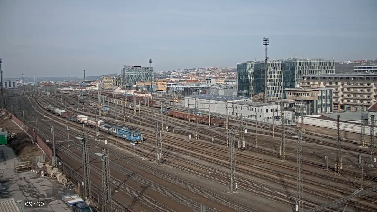 A sprawling railway yard with numerous train cars and tracks under a mostly clear sky.