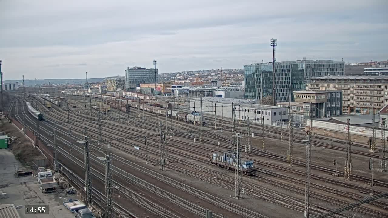 A sprawling railway yard with numerous train cars and tracks under an overcast sky.