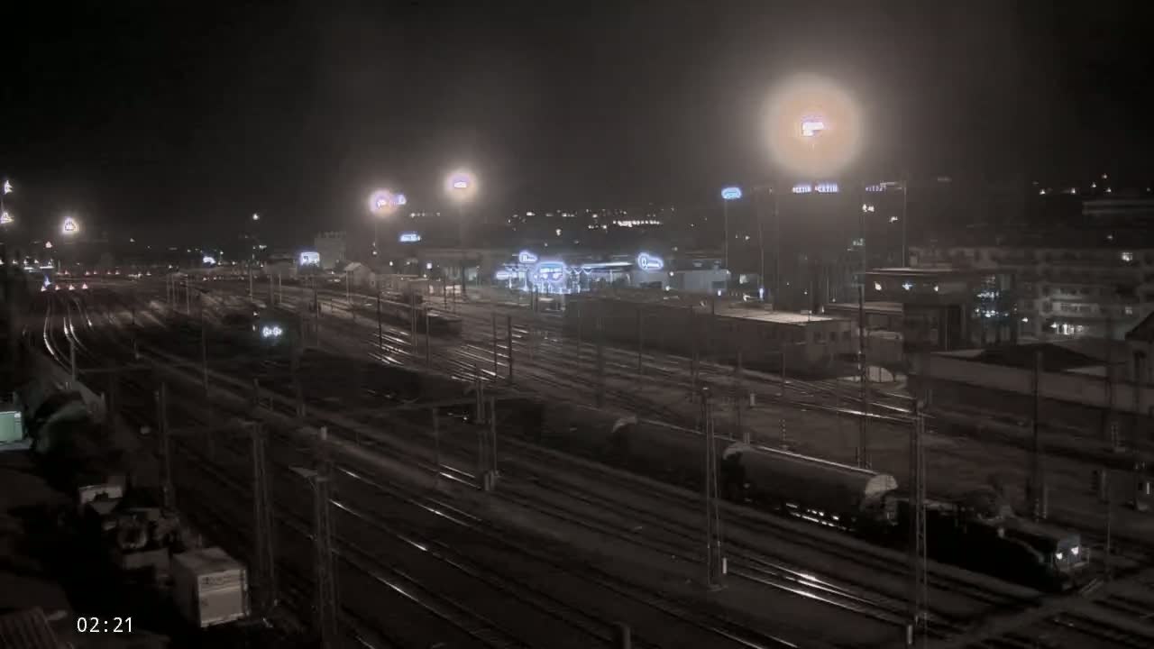 A nighttime view of a sprawling railway yard with numerous train cars and tracks, illuminated by artificial lights under a dark sky.