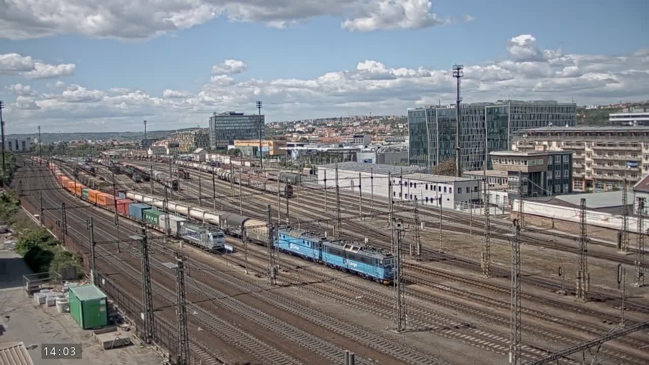 A large railway yard with numerous trains and freight cars under a partly cloudy sky.