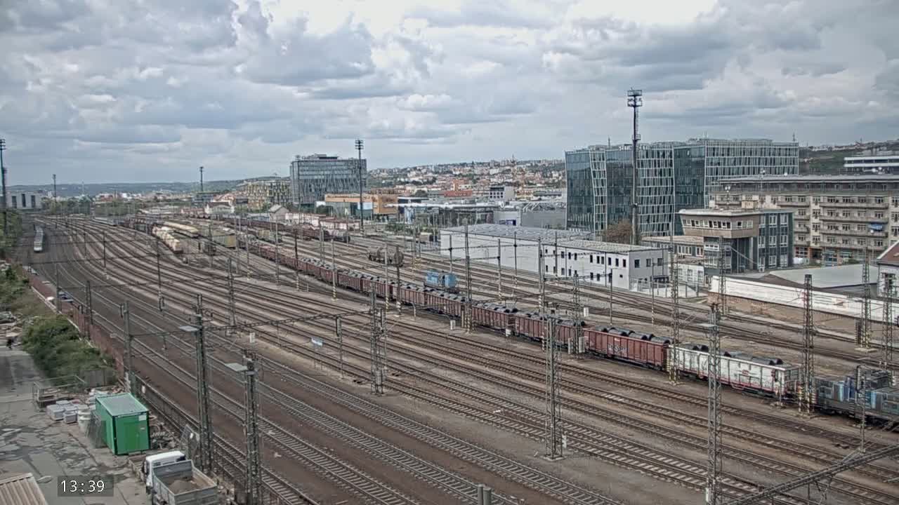 A sprawling railway yard with numerous train cars and tracks under a cloudy sky.