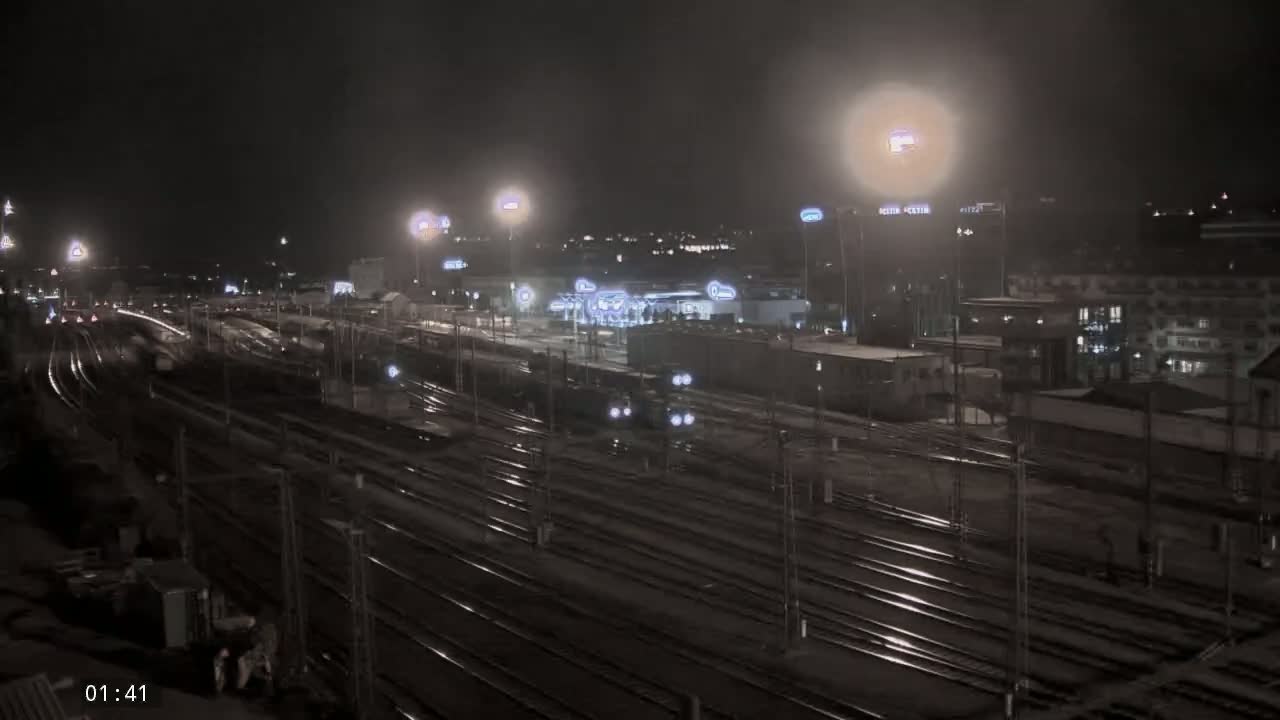 A nighttime view of a train yard with many tracks and a train moving through the dimly lit area.