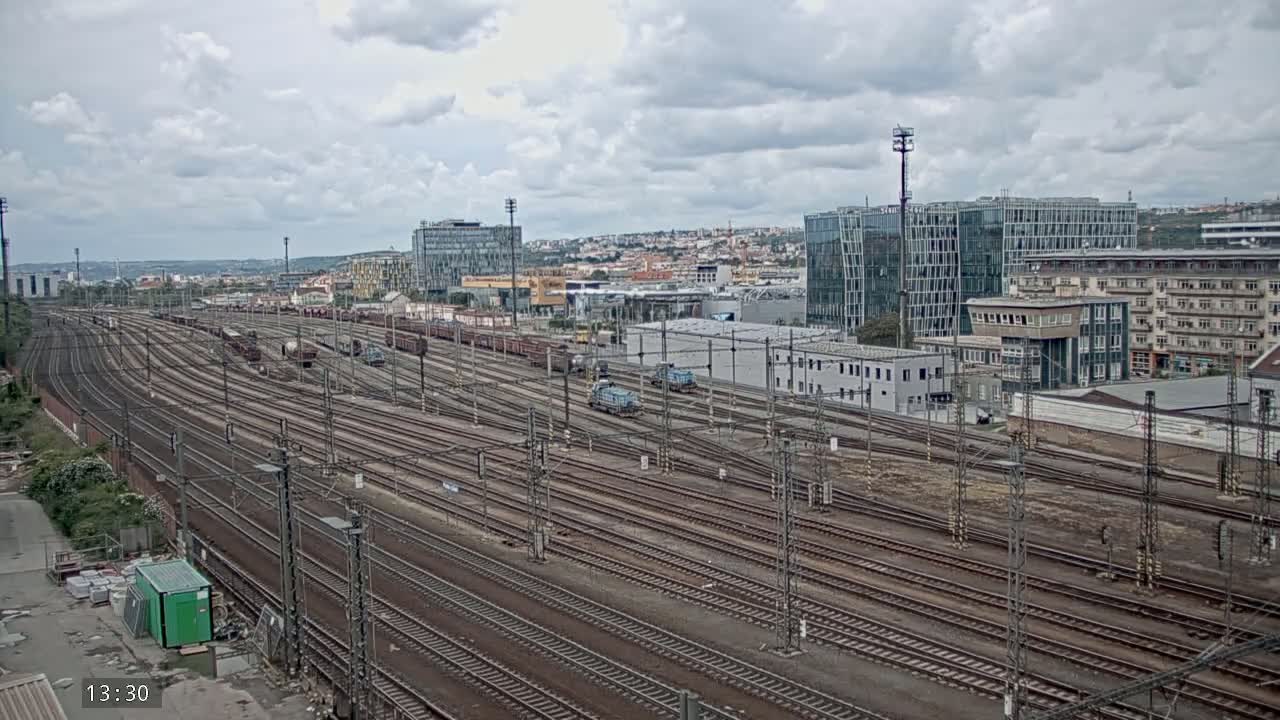 A sprawling railway yard with numerous train tracks and freight cars under a cloudy sky.