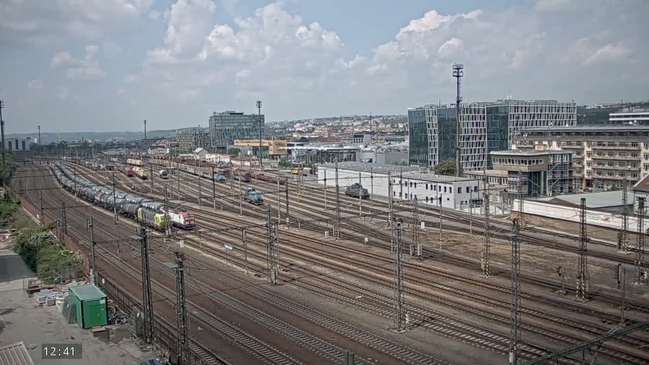 A sprawling railway yard with numerous train cars and tracks under a partly cloudy sky.