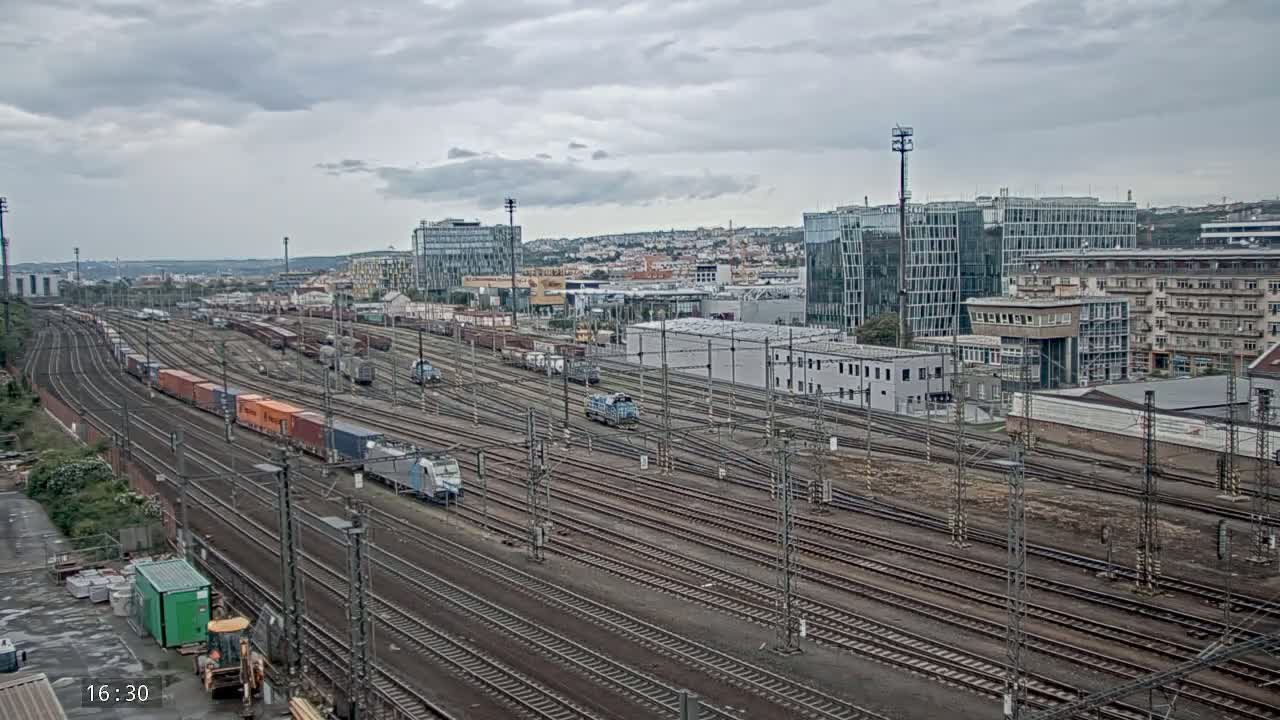 A sprawling railway yard with numerous trains and cargo containers under an overcast sky.