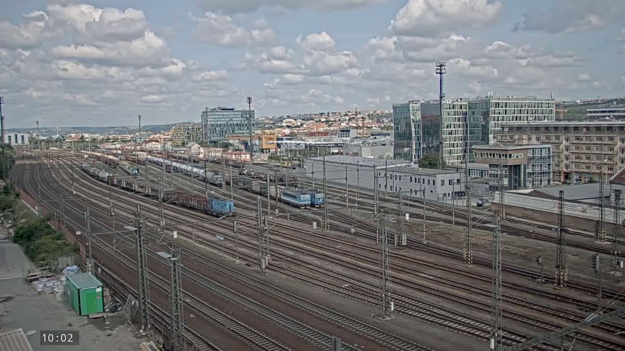 A sprawling railway yard with numerous train cars and locomotives under a partly cloudy sky.