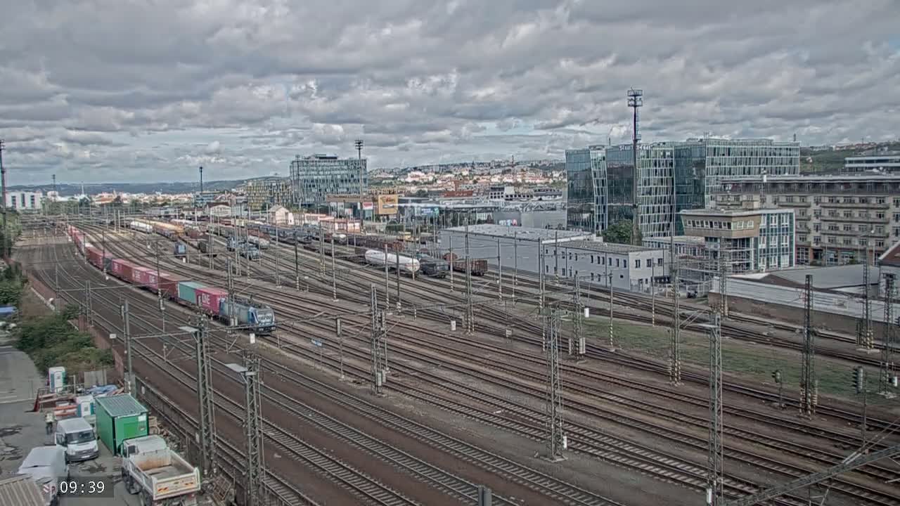 A large railway yard with numerous train tracks and freight trains under a cloudy sky.