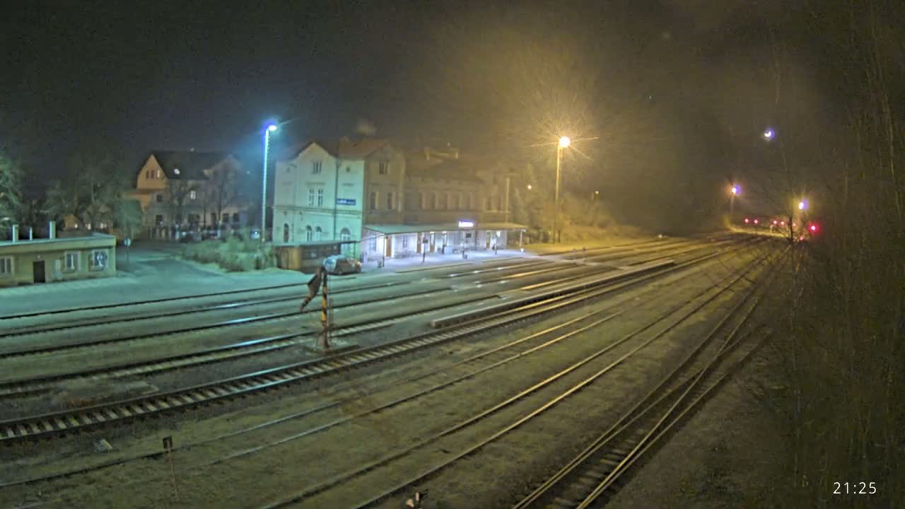 A nighttime view of a train station with multiple tracks extending into the distance under hazy conditions.