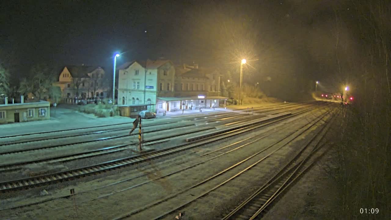 A nighttime view of a train station with multiple train tracks extending into the distance under a clear, starlit sky.