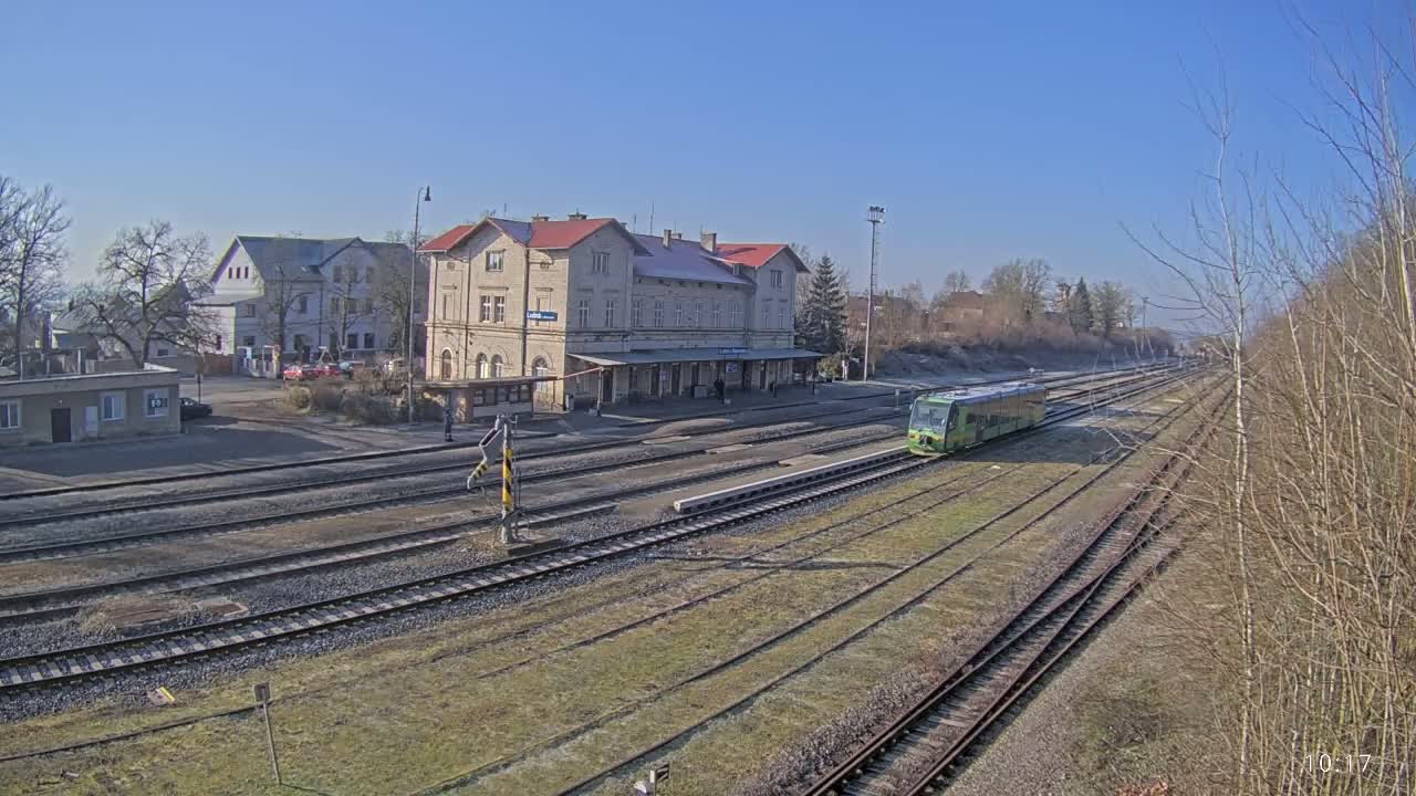 A light-green train is arriving at a train station on a sunny day.