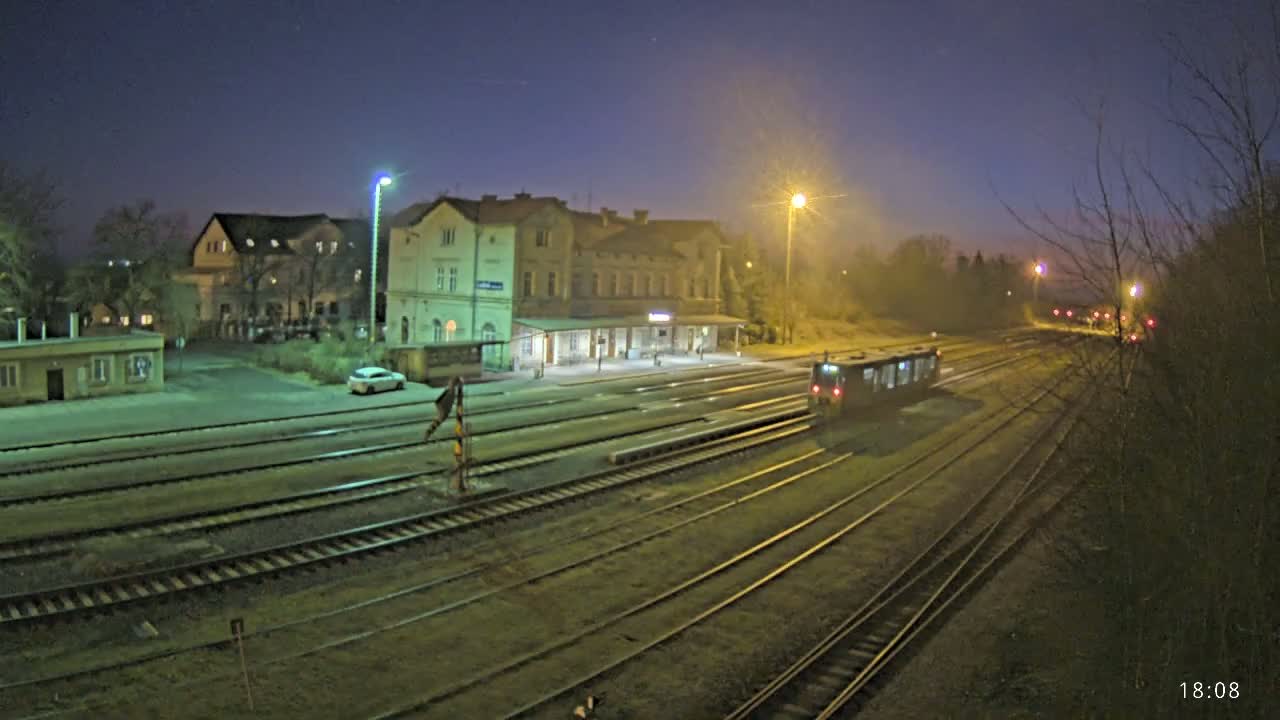 A train sits in a station at night under a dark, clear sky next to a long building.