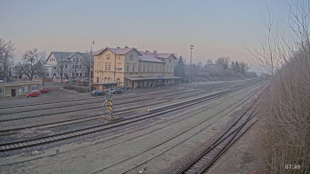A train station with a long expanse of railway tracks stretches into the distance on a cold, misty morning.