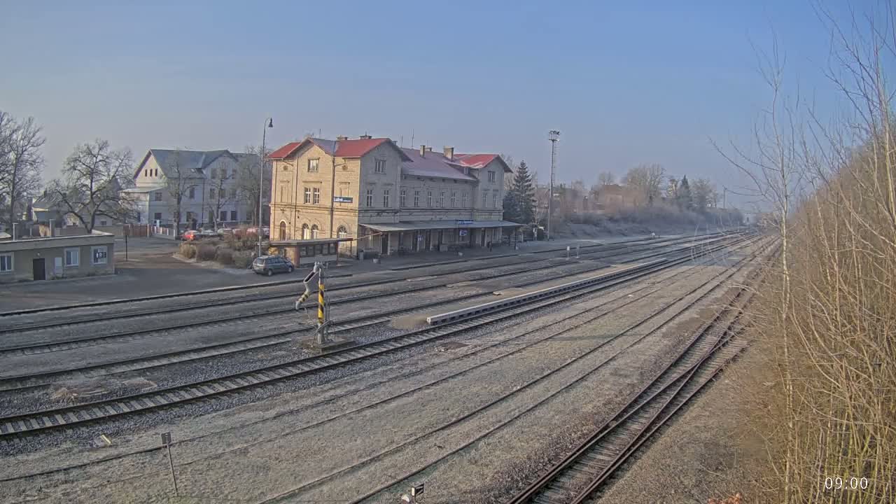 A long view of a train station on a clear, cold day shows multiple train tracks extending into the distance, with a large building in the center and other buildings visible in the background.