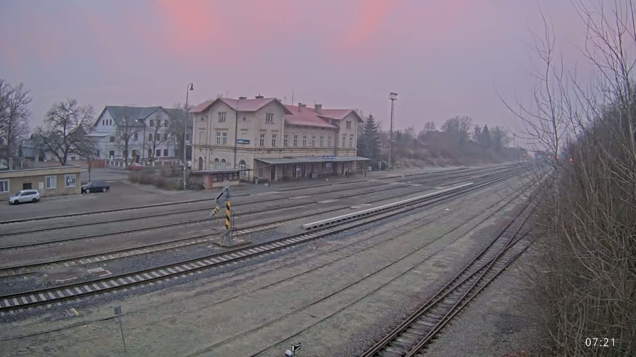 A long view of a train station with multiple tracks under a pinkish-gray sky.
