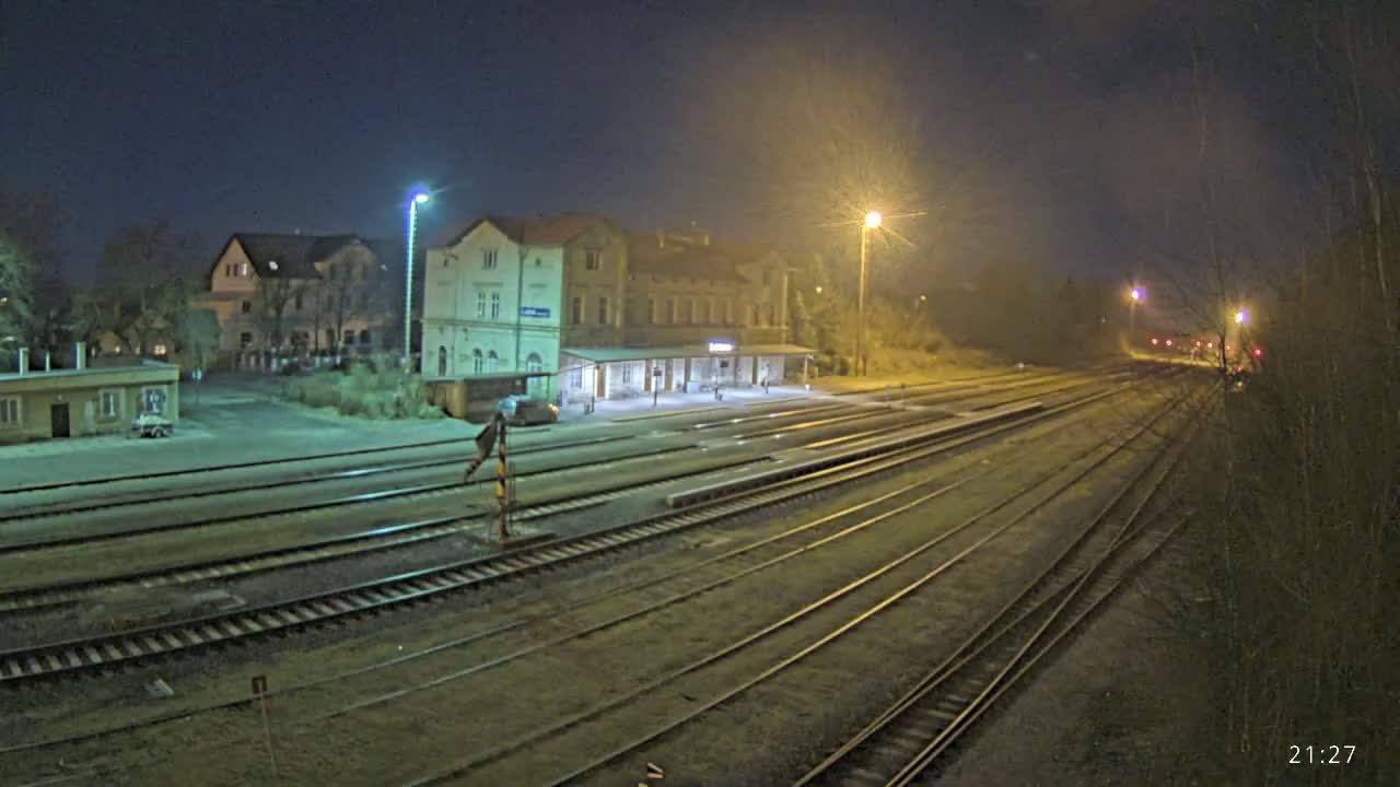 A nighttime view of a train station with multiple tracks extending into the distance under a dark, clear sky.