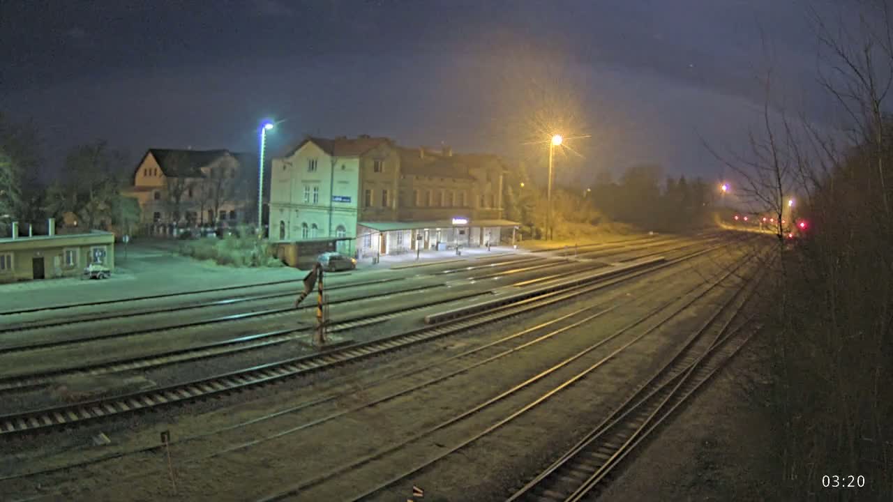 A nighttime view of a train station with multiple tracks extending into the distance under a hazy sky.