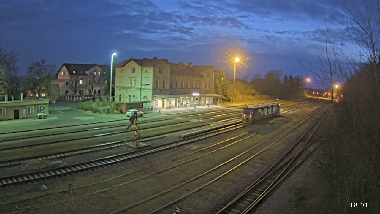 A train sits in a dimly lit train station at twilight under a partly cloudy sky.