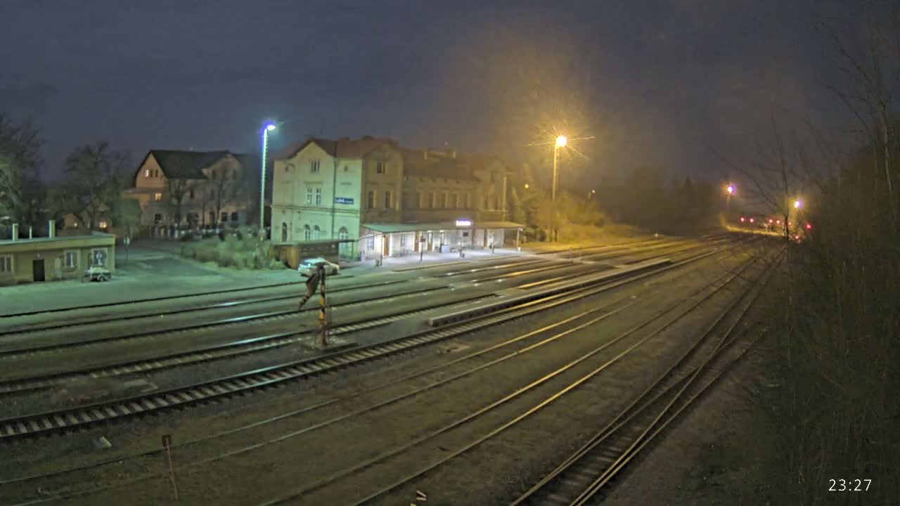 A nighttime view of a train station with several tracks extending into the distance under hazy, dimly lit conditions.