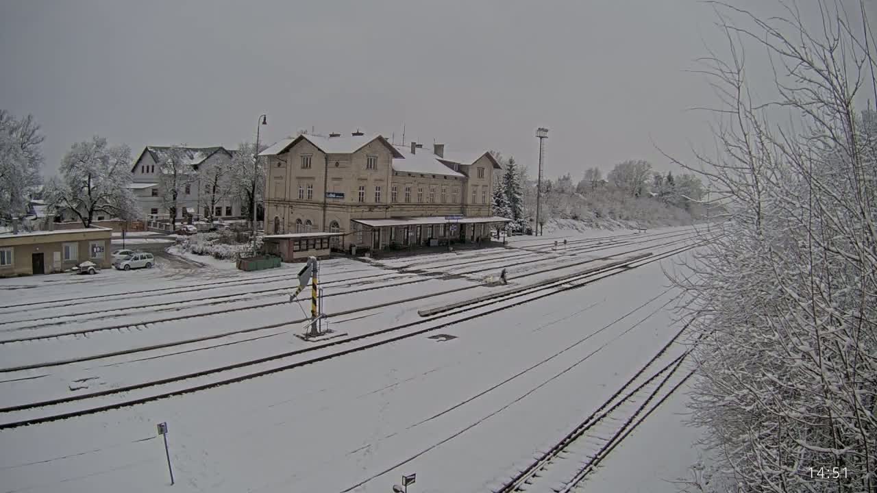 A snow-covered train station and its surrounding area are seen on a cloudy day.