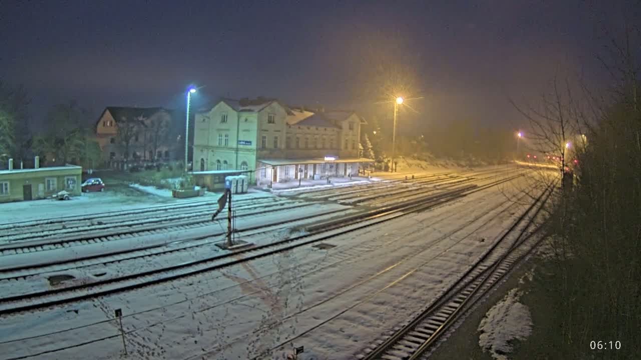 A snow-covered train station at night, illuminated by streetlights.