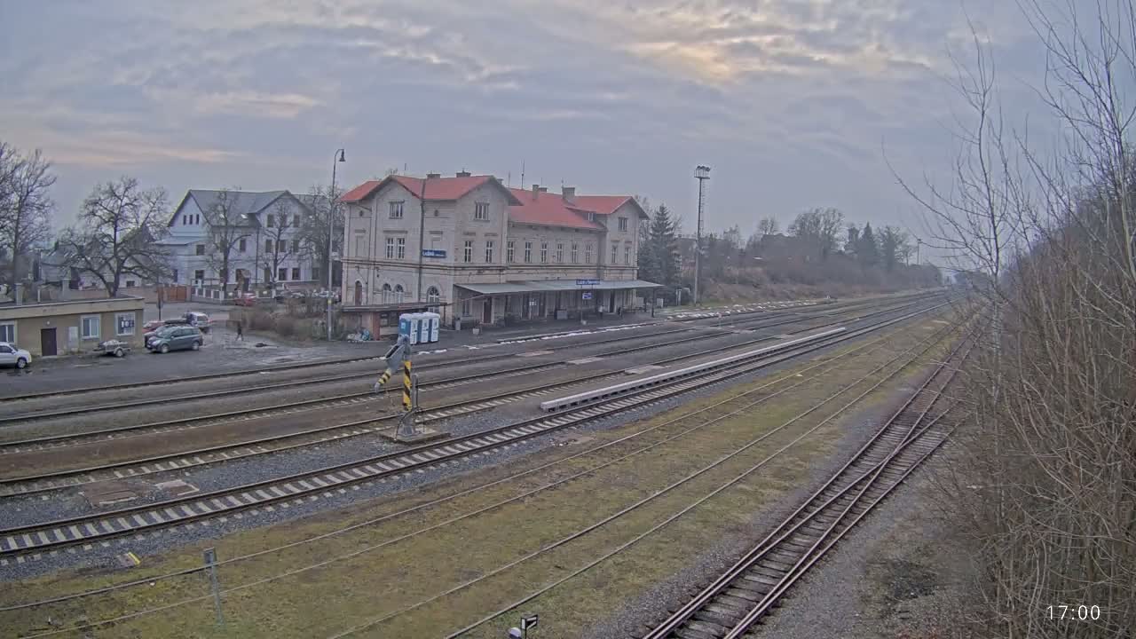 A train station with a long platform and multiple train tracks under an overcast sky.