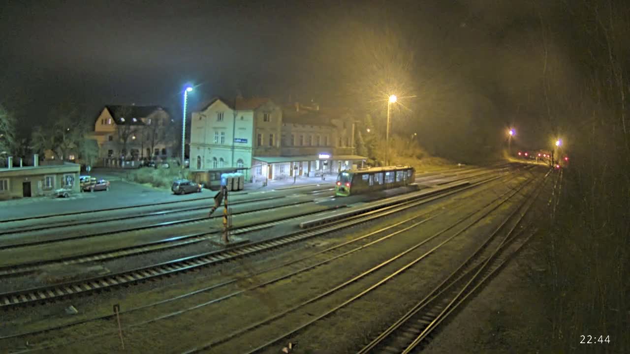 A train sits at a station at night under dim lighting, with several tracks extending into the distance.