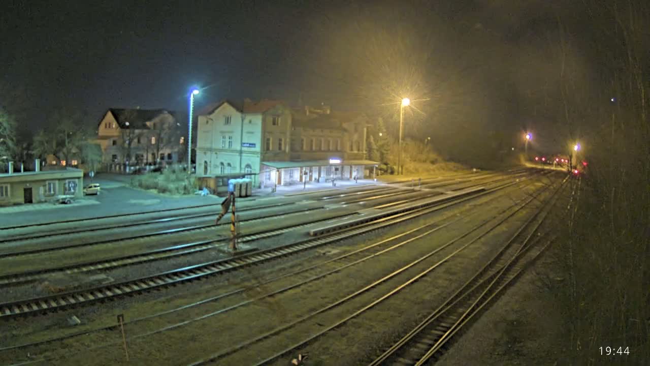 A nighttime view of a train station with several tracks extending into the distance under a dark sky.