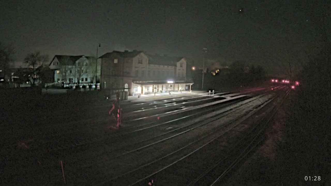 A nighttime view of a train station with several tracks extending into the distance, under a dark, clear sky.