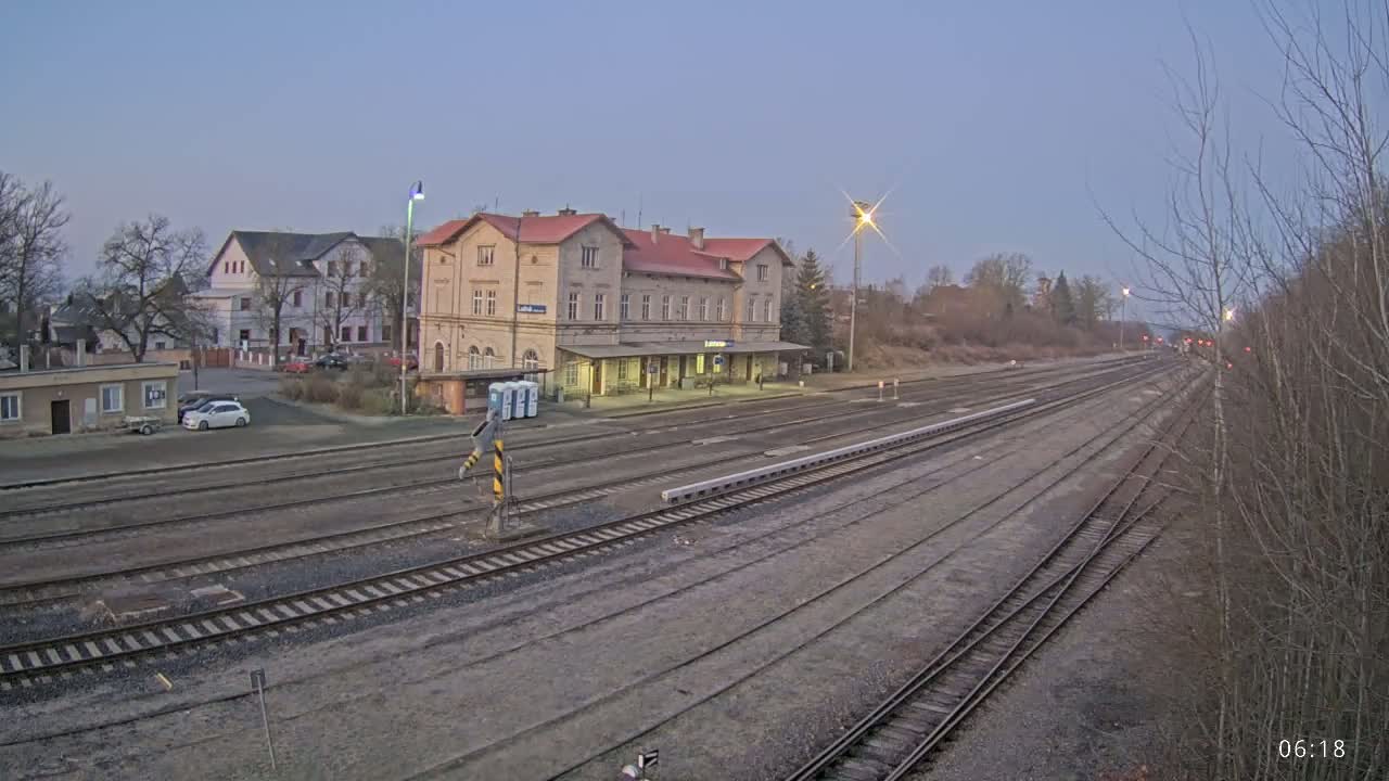 A long view of a train station and multiple train tracks under a twilight sky.