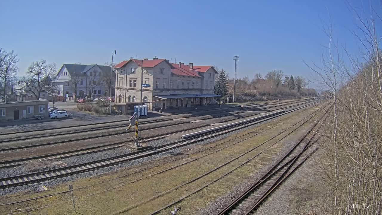 A long view of a train station building and multiple train tracks on a sunny day.