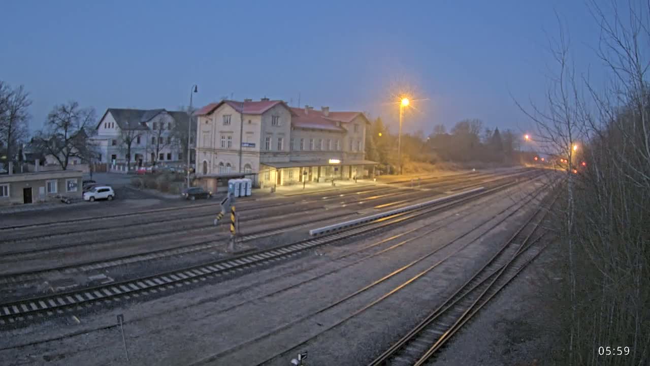 A long view of a train station at dusk, with several train tracks extending into the distance under a twilight sky.
