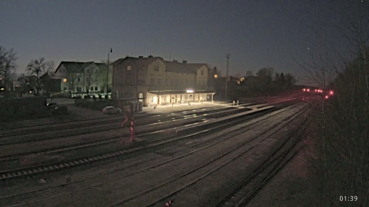 A nighttime view of a train station with multiple train tracks extending into the distance under a dark, clear sky.