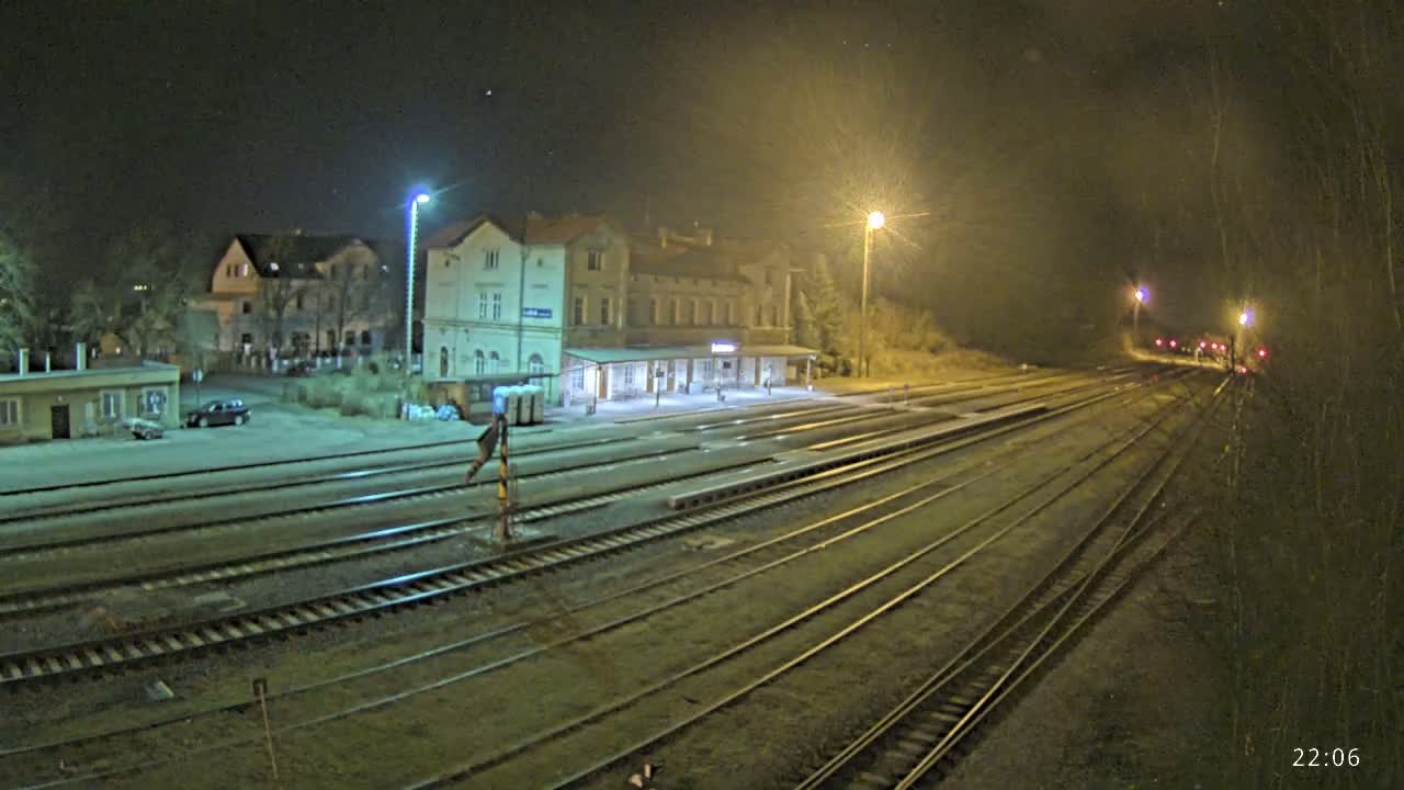 A nighttime view of a train station with multiple tracks extending into the distance under a slightly hazy sky.