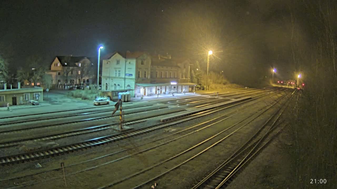 A nighttime view of a train station with several tracks extending into the distance under artificial light.