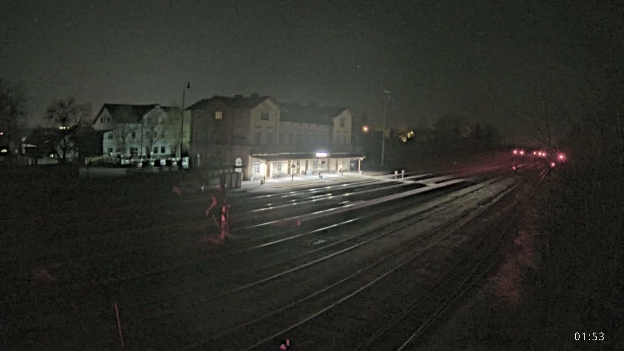 A nighttime view of a train station with several tracks extending into the distance under a clear, dark sky.