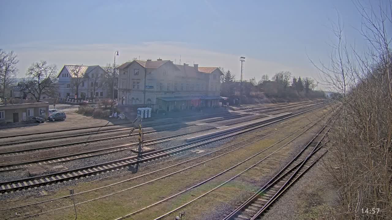 A long view of a train station with several tracks extending into the distance under a clear, sunny sky.