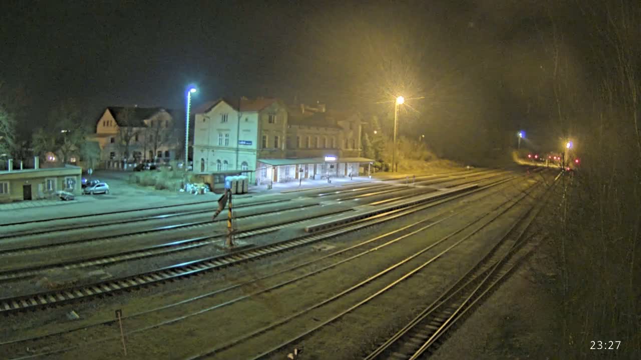 A nighttime view of a train station with multiple tracks extending into the distance under artificial lighting.