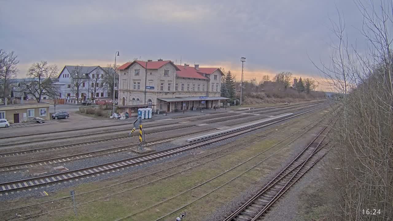 A long view of a train station building and several sets of train tracks under an overcast sky.