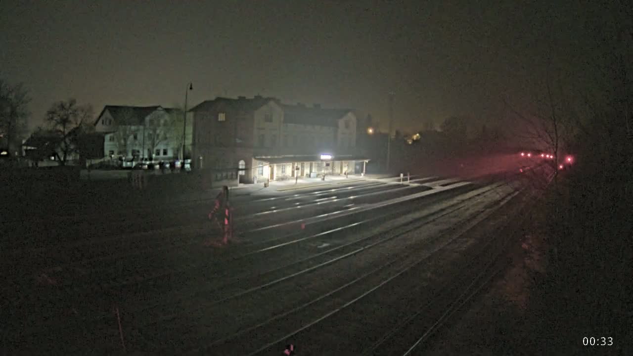 A nighttime, foggy view of a train station with several tracks extending into the distance.