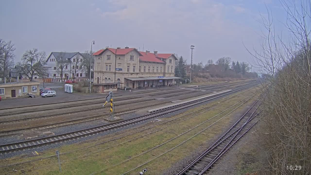 A long view of a train station with a large building and several tracks on an overcast day.