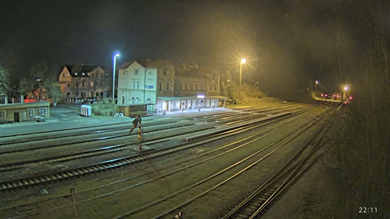 A nighttime view of a train station with multiple tracks extending into the distance under artificial light.