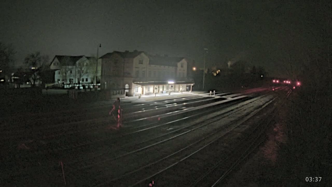 A nighttime view of a train station with several tracks extending into the distance under a dark, possibly overcast sky.