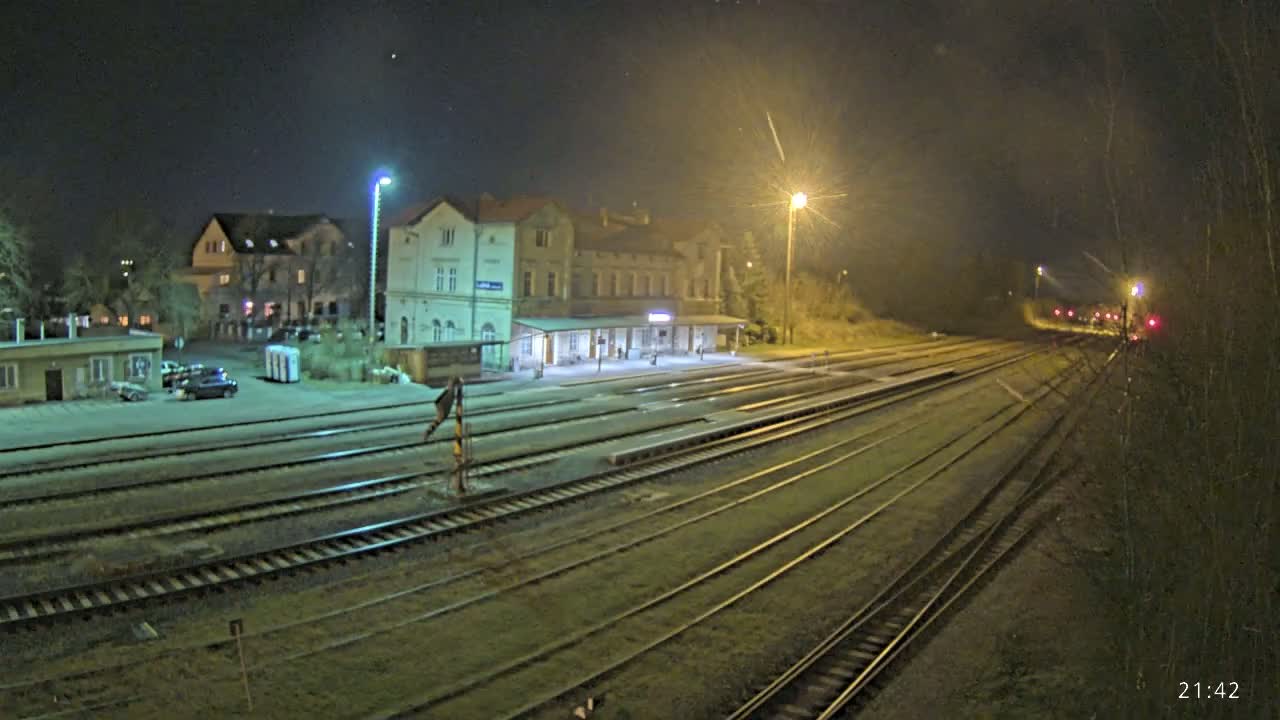 A nighttime view of a train station with several tracks extending into the distance, under a clear, dark sky illuminated by artificial lights.