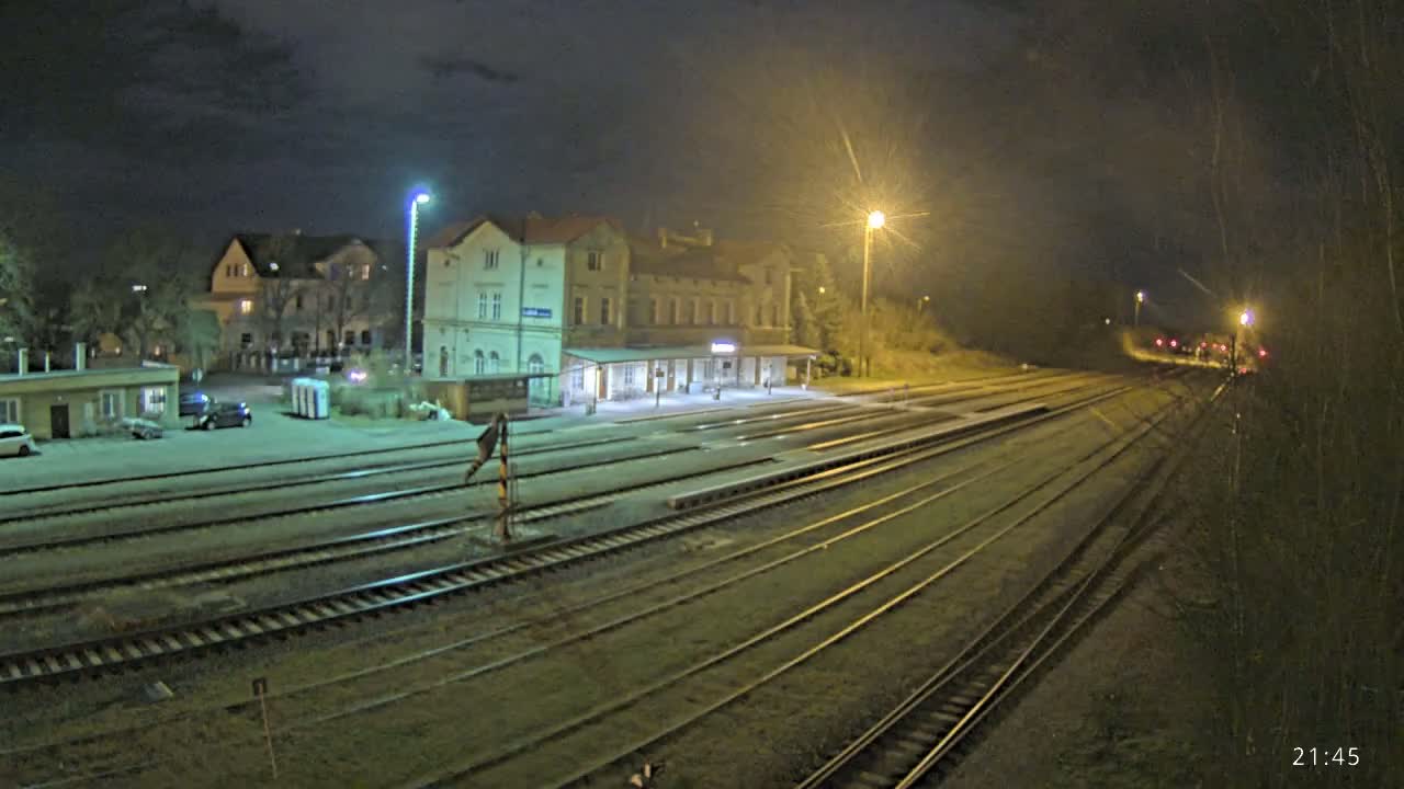 A nighttime view of a train station with multiple tracks extending into the distance under artificial light.