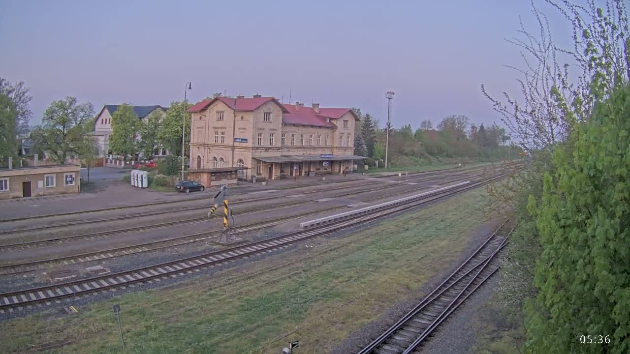 A long shot of a train station building and tracks under a pale, clear sky.