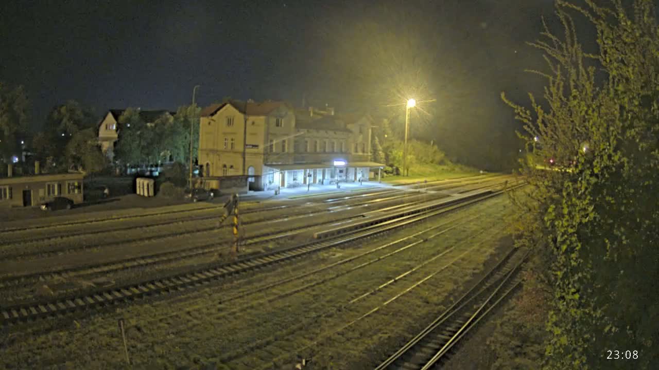 A nighttime view of a train station with multiple train tracks extending into the distance under artificial lighting.
