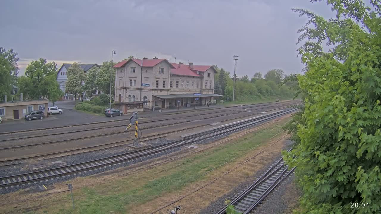 A long shot of a train station with several tracks under an overcast sky.